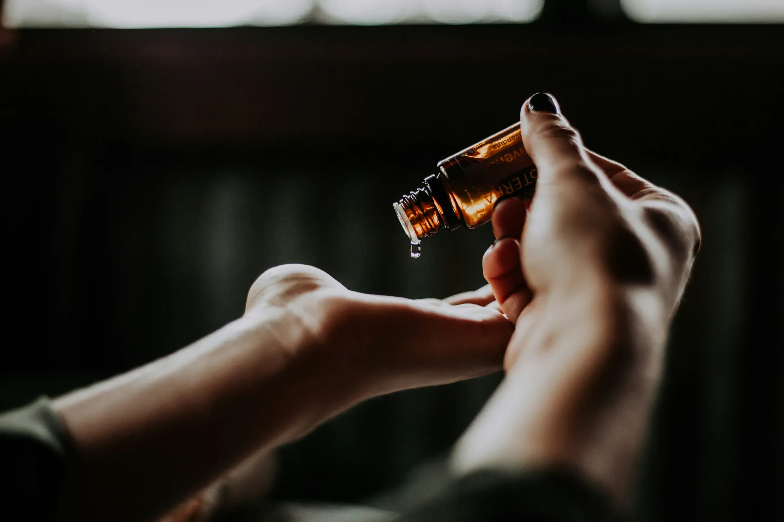 Person dispensing essential oil drops onto their palm
