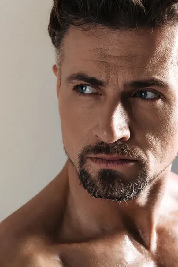 Portrait of a bearded man in his forties with bare shoulders, looking to the side