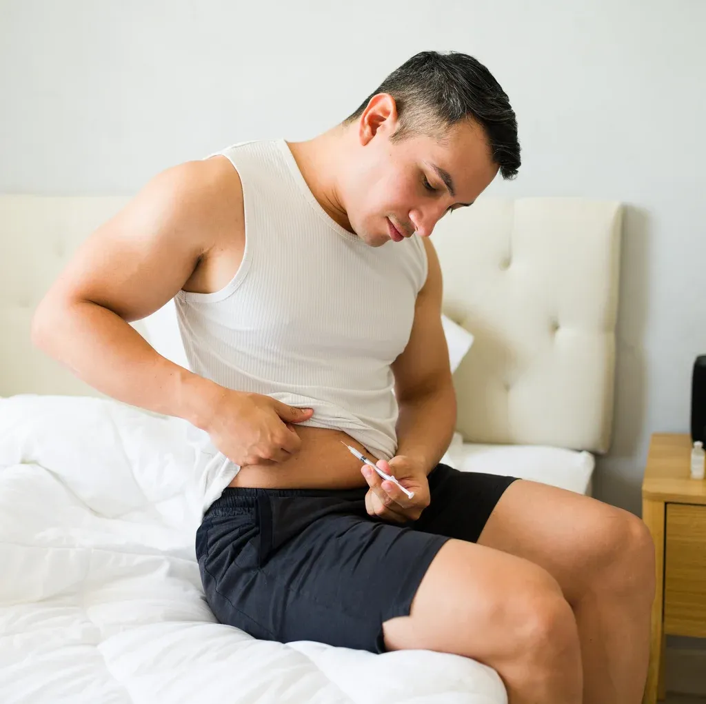 Man self-administering a peptide therapy injection at home — Ideal Medical, Aventura